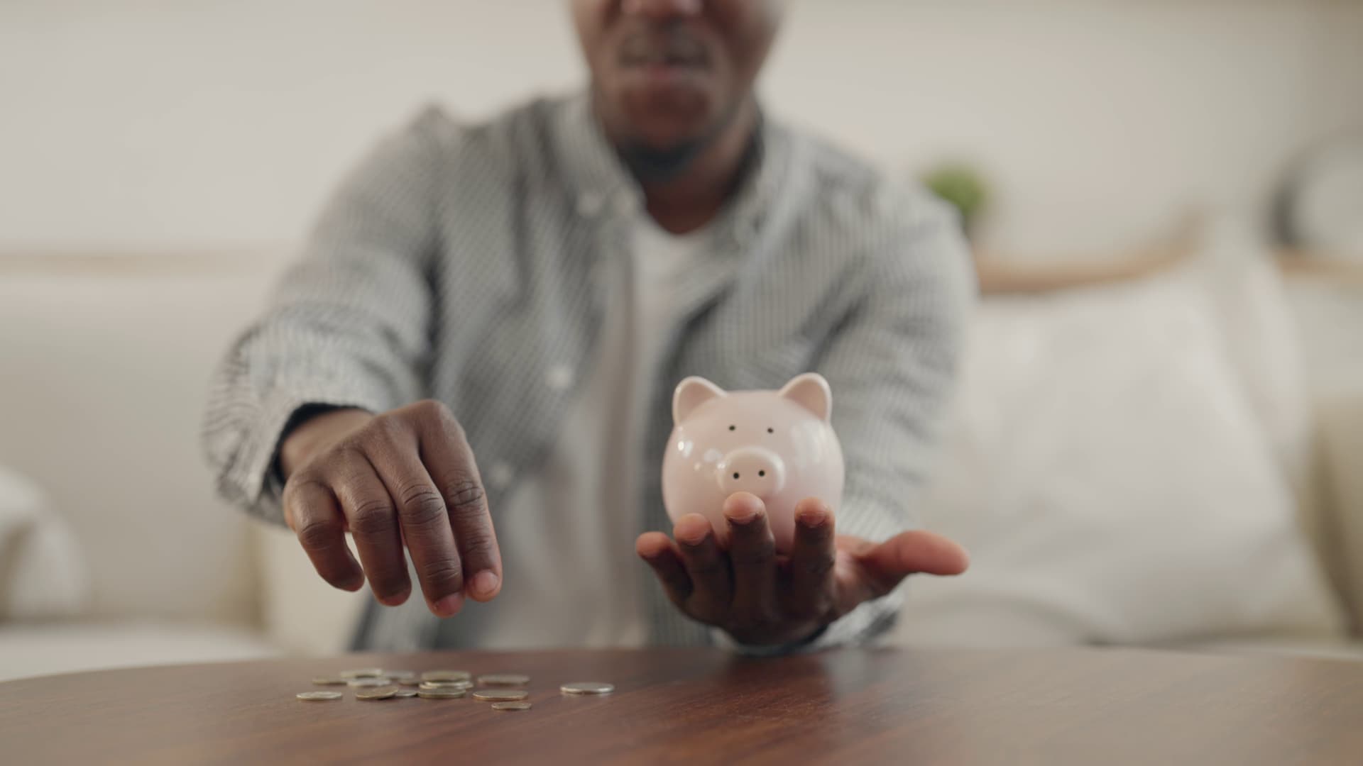 Young man putting coins into a piggy bank, building savings