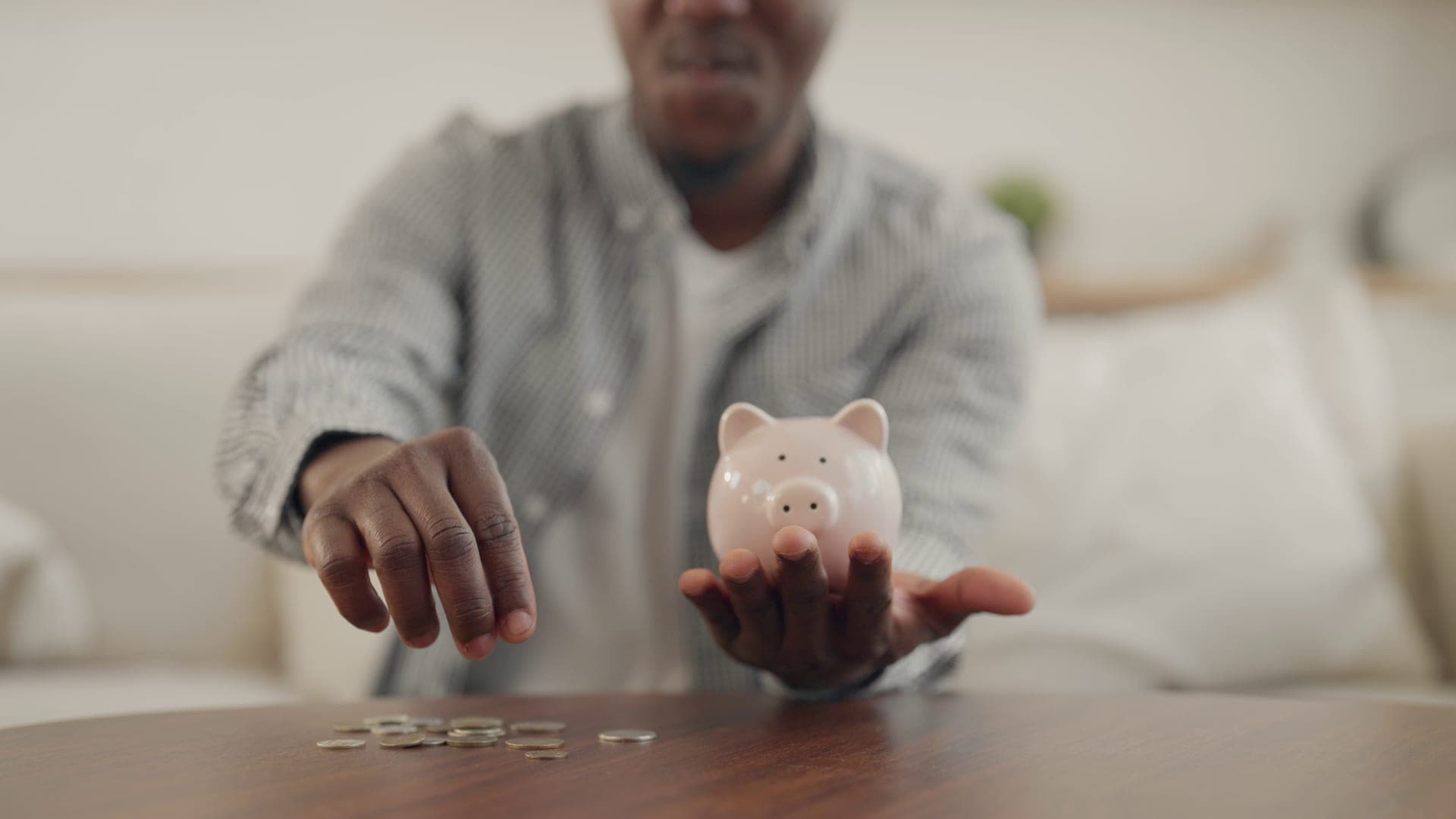 Young man putting coins into a piggy bank, building savings