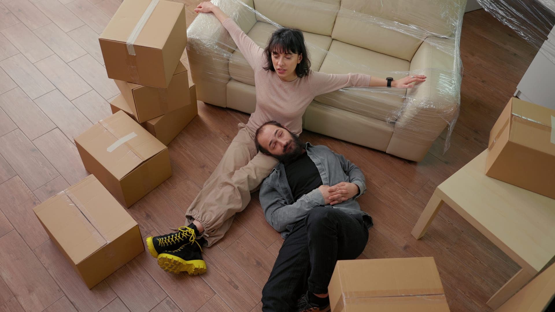 Couple relaxing on floor surrounded by moving boxes in new apartment