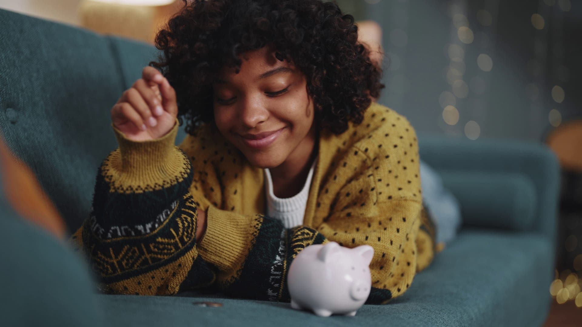 Happy woman adding coins to piggy bank
